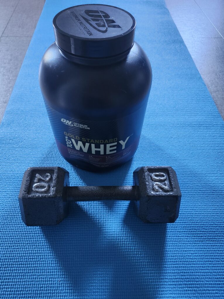 Protein powder and a weight on a blue mat
