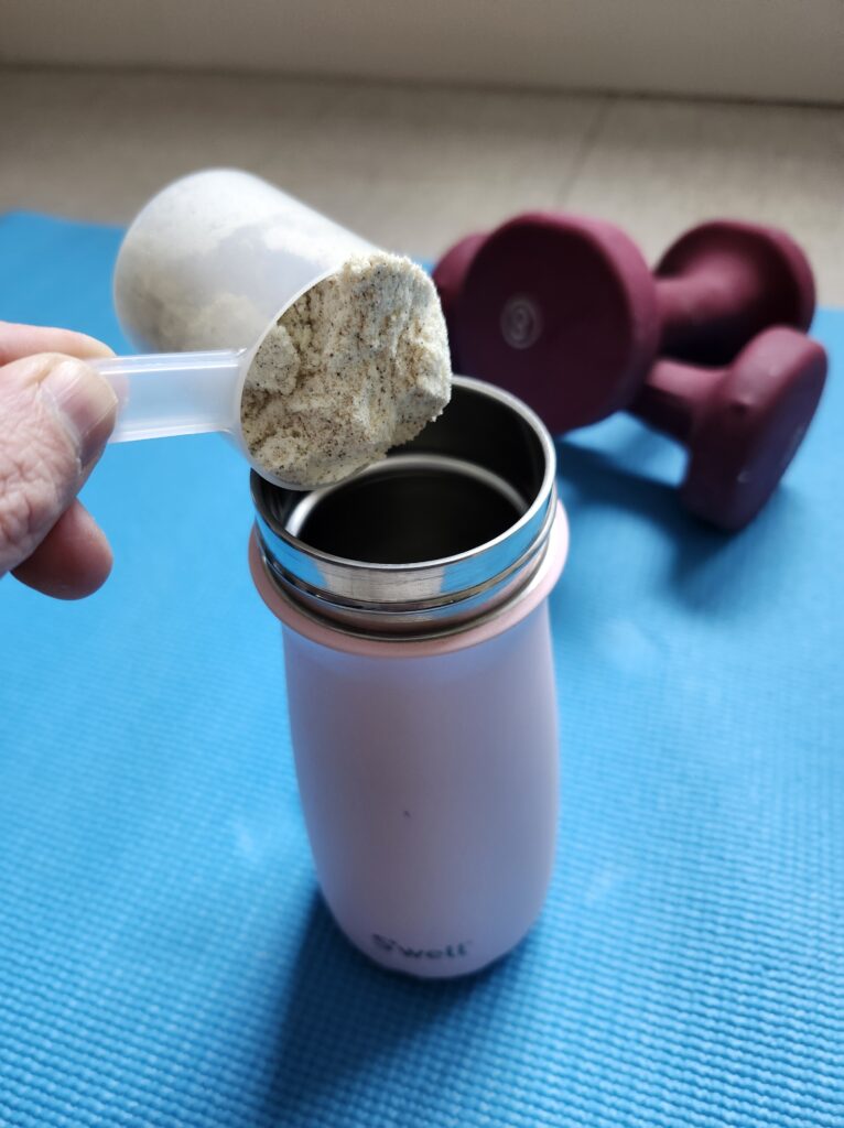 Preparing protein shake after working out on a blue mat with dumbbells